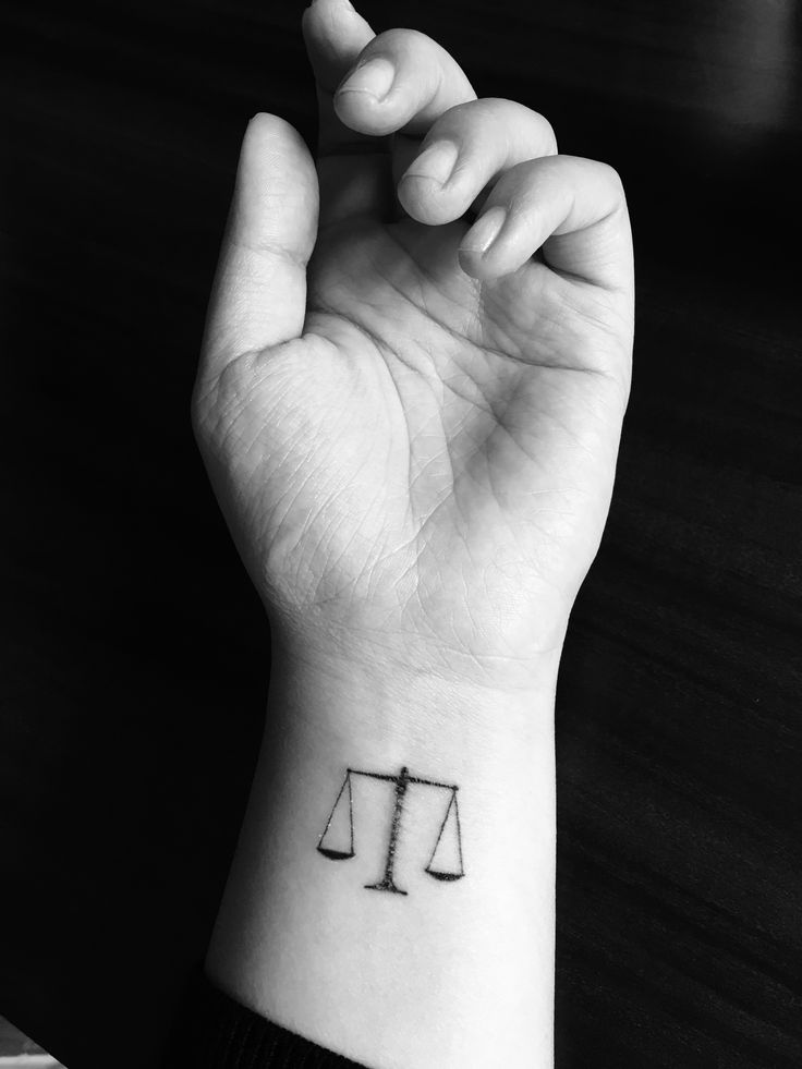 a black and white photo of a person's hand with a tattoo on it