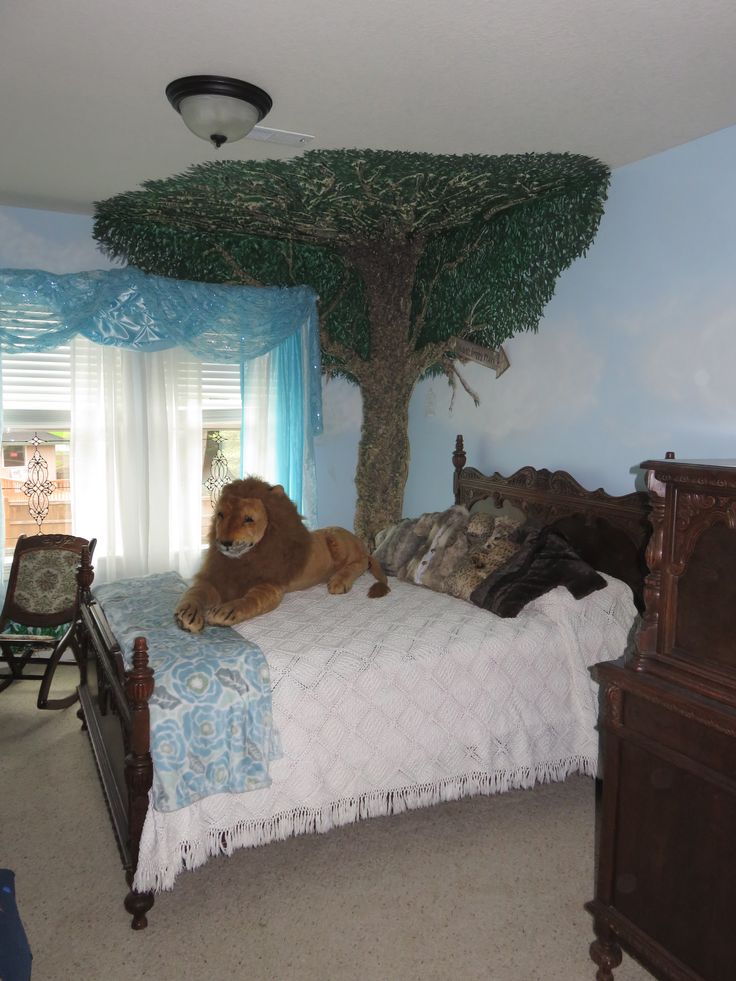 a large brown dog laying on top of a bed in a bedroom next to a tree