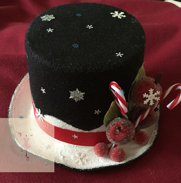 a black top hat with candy canes and candies on the side sitting on a red table cloth