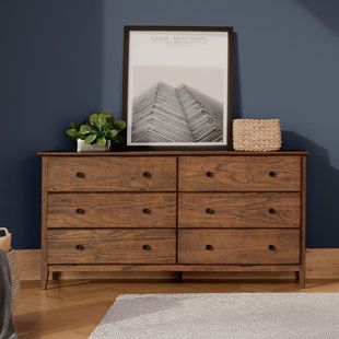 a wooden dresser sitting on top of a hard wood floor next to a blue wall