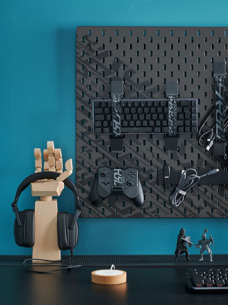 a computer desk with a keyboard, mouse and headphones on it next to a wall mounted video game controller