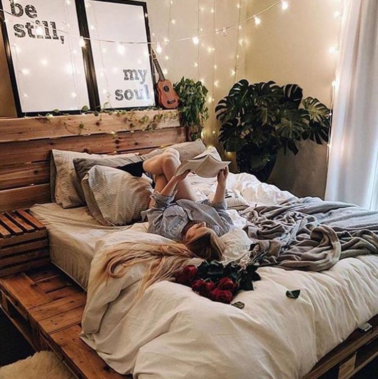 a woman laying on top of a bed in a bedroom next to a potted plant