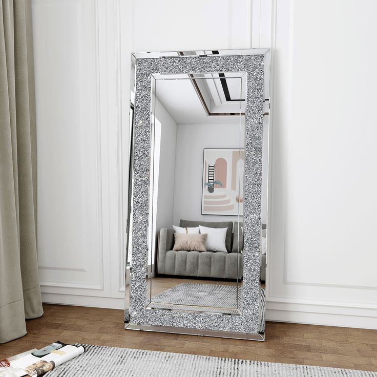 a large silver mirror sitting on top of a wooden floor next to a couch in a living room