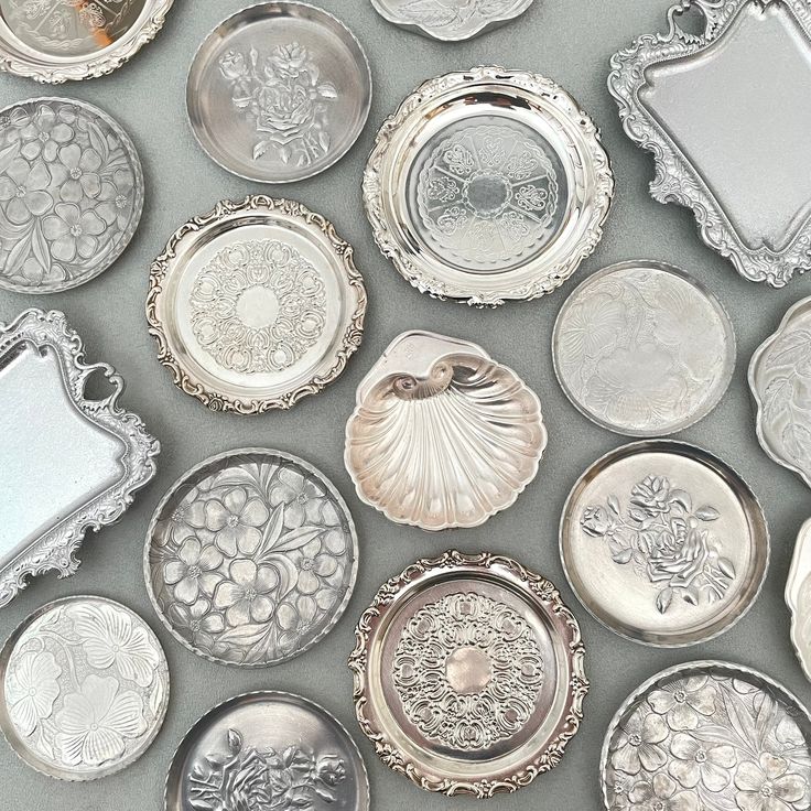 many silver plates and trays with designs on them