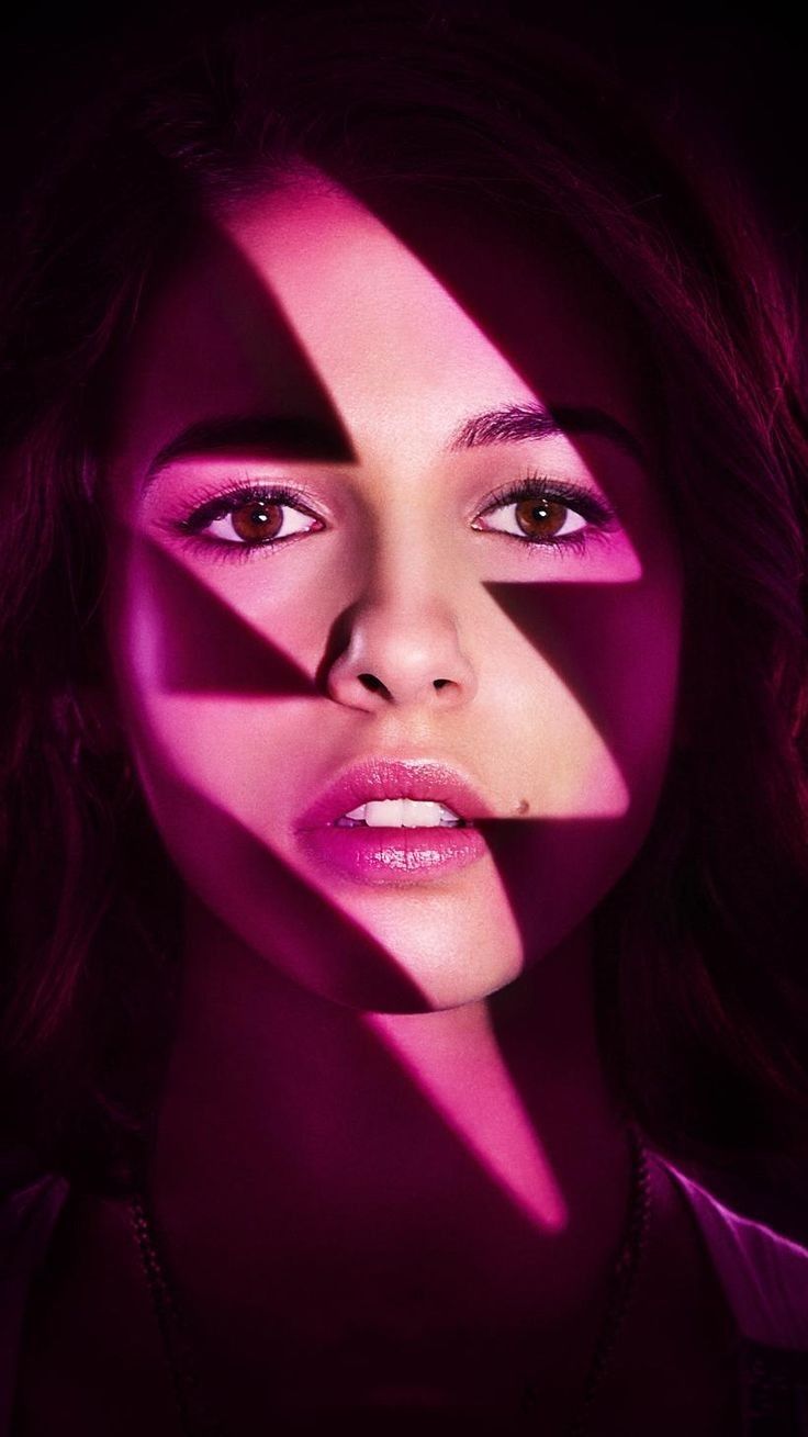 a woman's face is shown through the shadow of a pink light