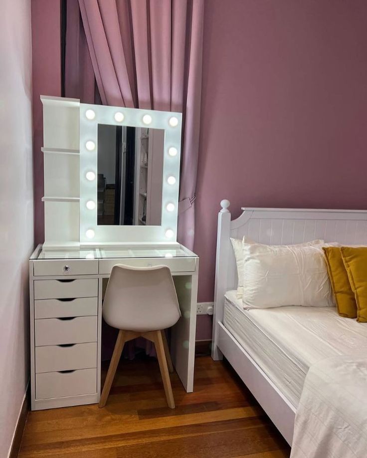 a bedroom with a bed, desk and vanity mirror in front of a purple wall