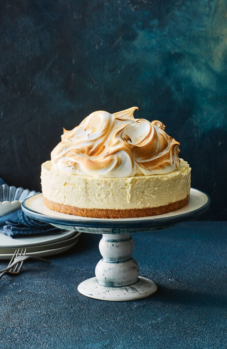 there is a cake on the table with two plates next to it and a blue background