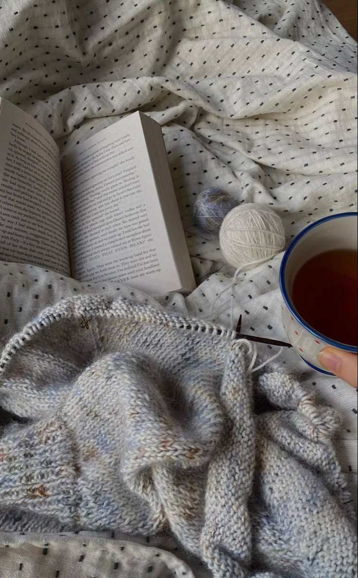 a cup of tea and an open book on a bed