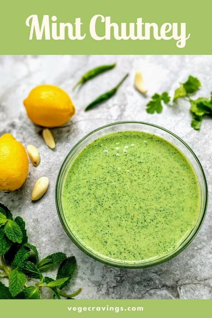 a green smoothie in a glass surrounded by lemons, mint and pine nuts