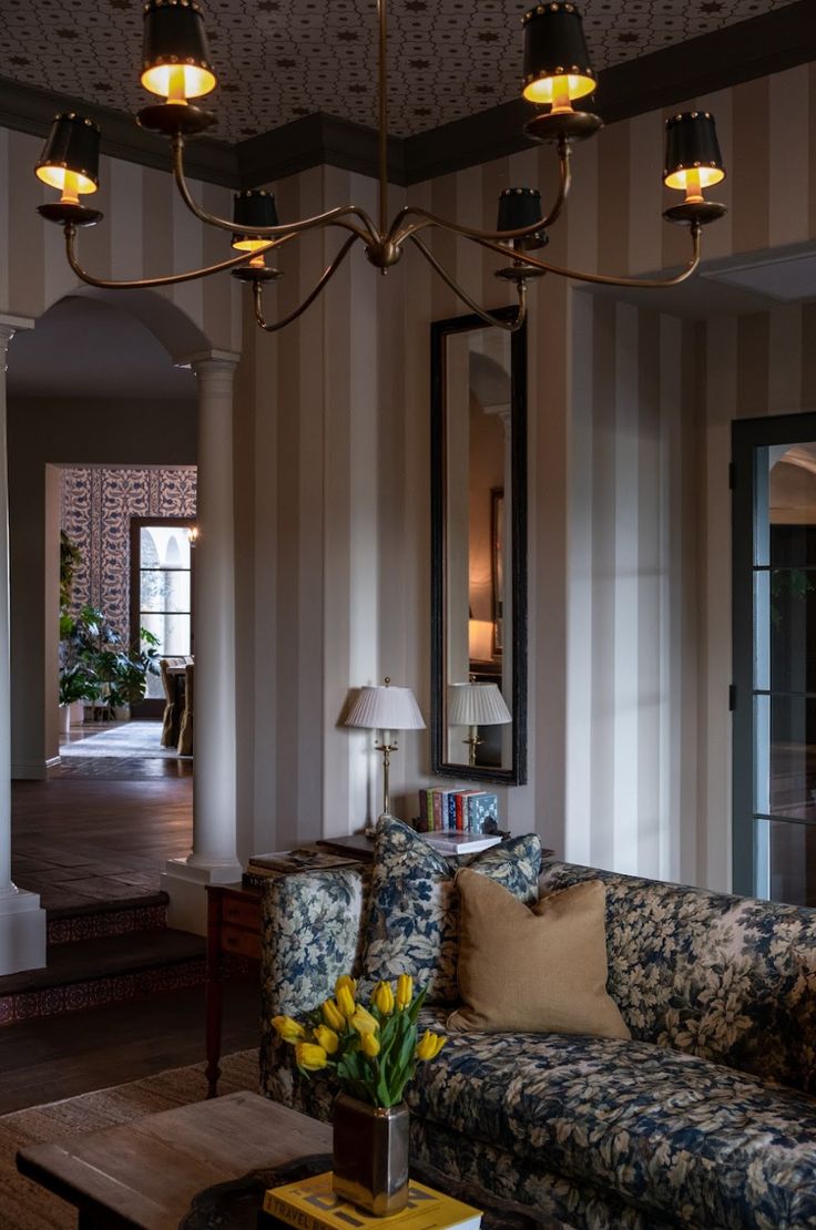 a living room filled with furniture and a chandelier hanging over the top of it