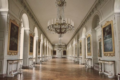 an ornate hall with chandeliers and paintings on the walls, along with wooden floors