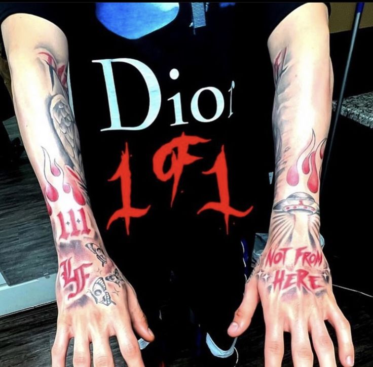 a man with tattoos on his arms and hands is wearing a black t - shirt