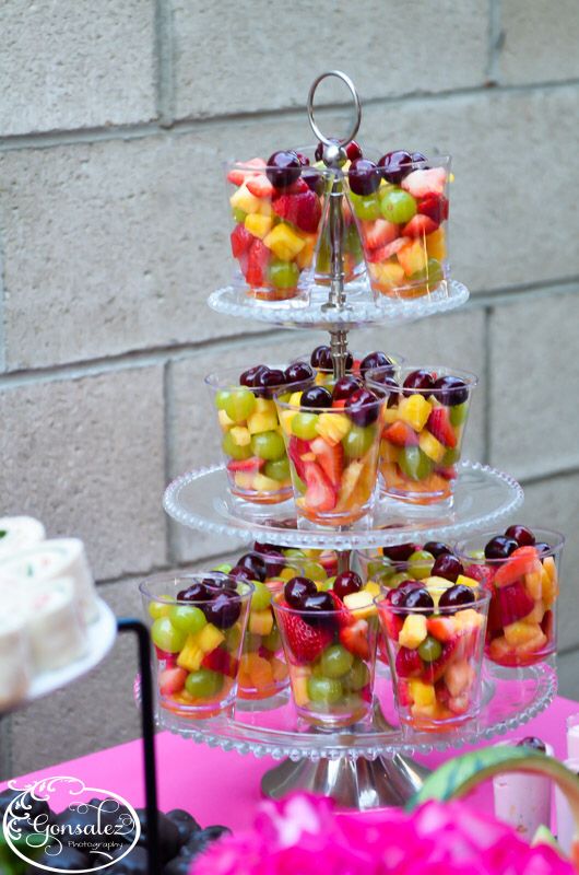 a three tiered cake stand filled with cupcakes and fruit