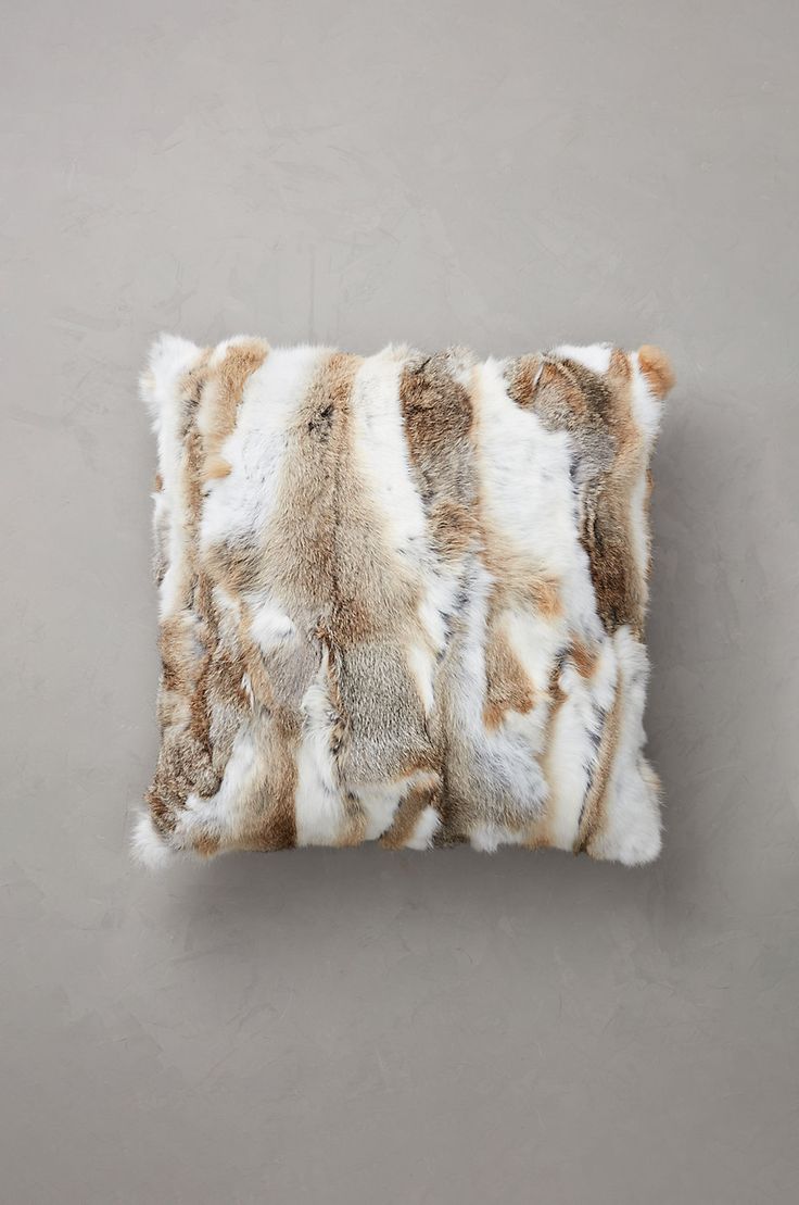 an animal print pillow on a gray wall with white and brown fur trimmings