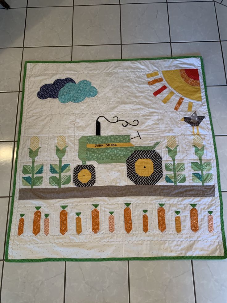 a quilted placemat with a tractor and farm animals on it, sitting on a tile floor