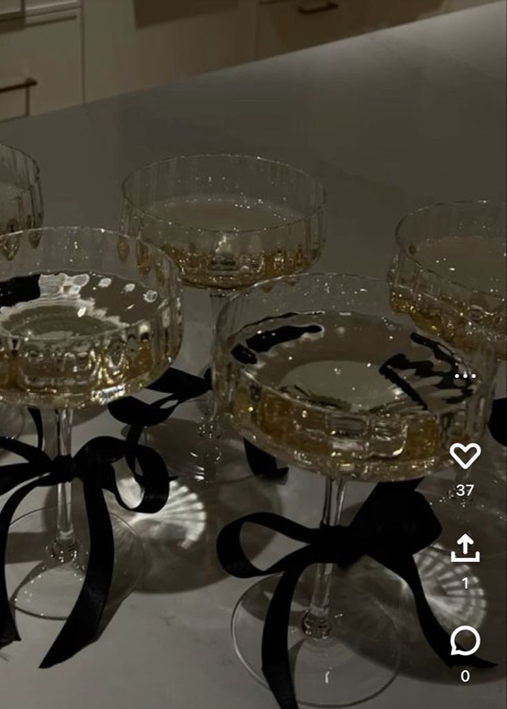 four wine glasses sitting on top of a table with black ribbon around the rims