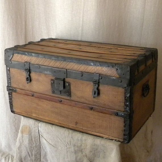 an old wooden trunk sitting on top of a stone wall next to a white curtain