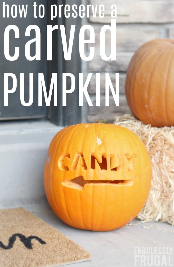 a carved pumpkin sitting on top of hay next to a door with the words carved pumpkin