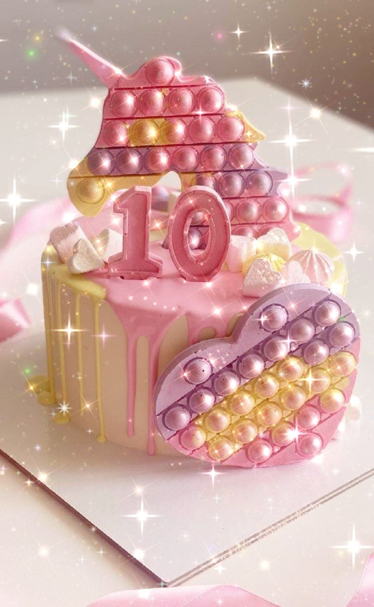 a pink and gold birthday cake with the number 10 on it's top is surrounded by pearls