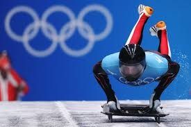 a man riding a skateboard down a snow covered slope next to the olympic rings