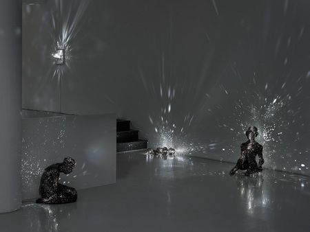 two black and white sculptures sitting on top of a floor next to a wall filled with fireworks