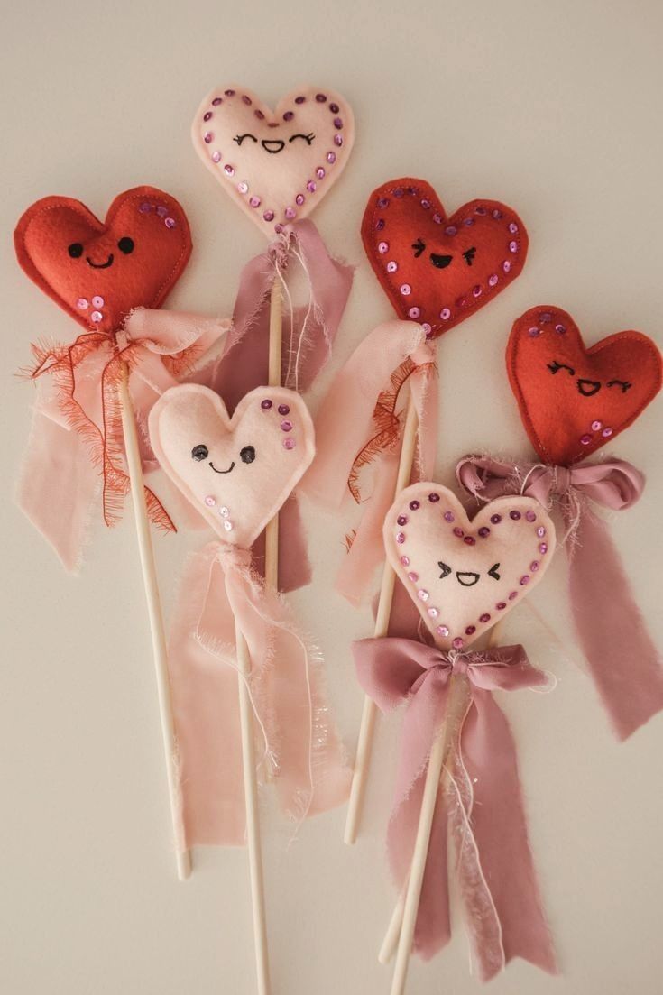 four heart - shaped lollipops with bows and sequins on them