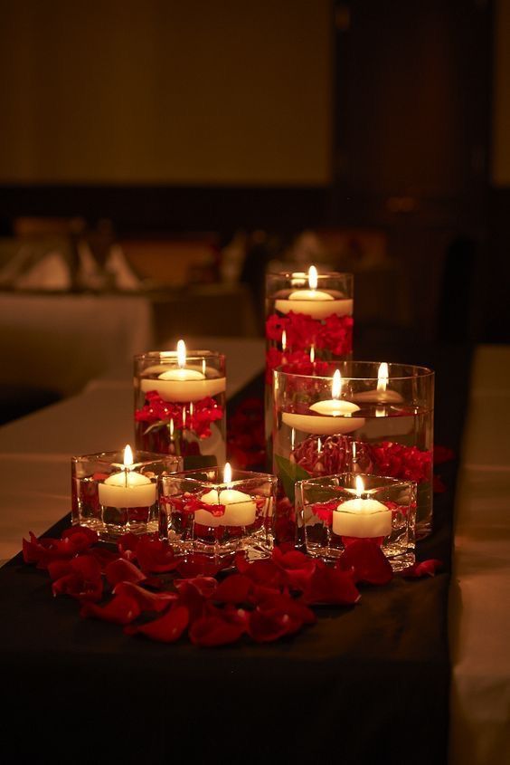 a table with candles and flowers in vases on it's centerpiece, surrounded by other place settings