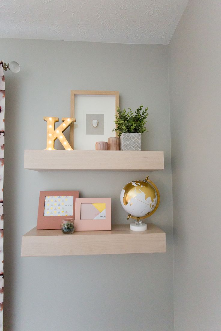 two shelves with pictures and other items on them in a room that is painted light gray