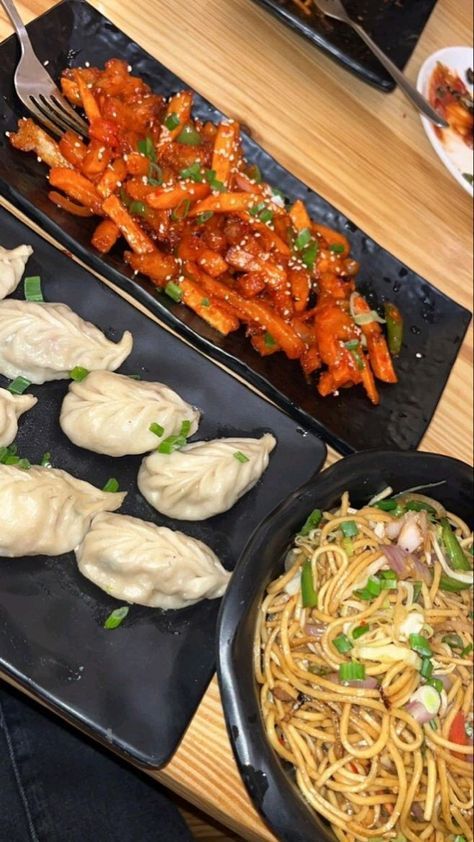 some food is sitting on black trays next to other plates and pans with different foods