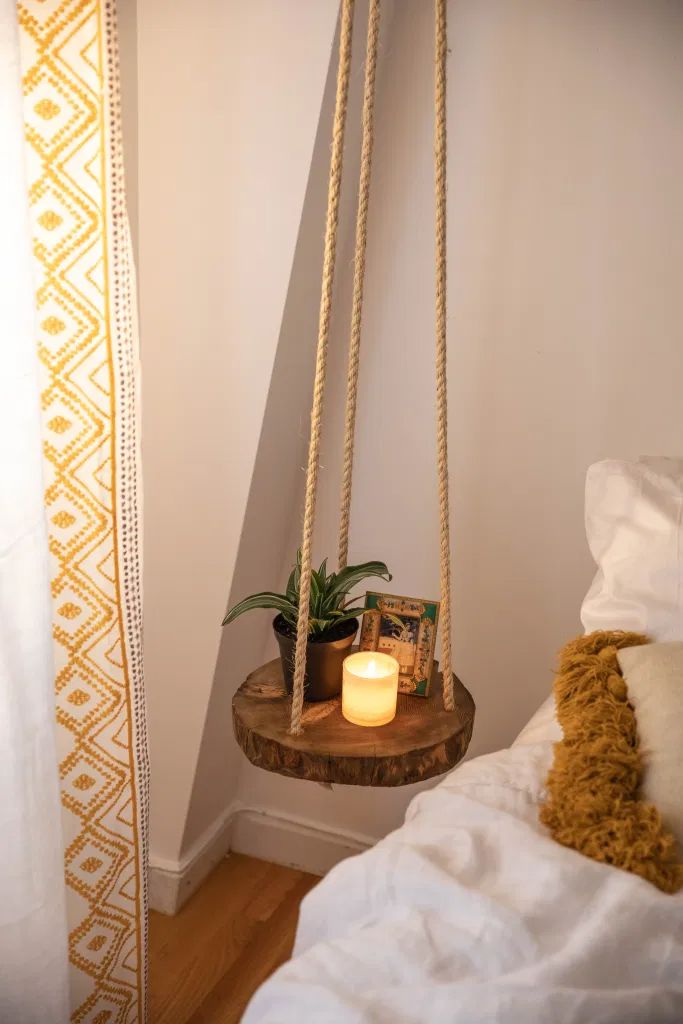 a candle is lit on a swing in the corner of a room with white walls