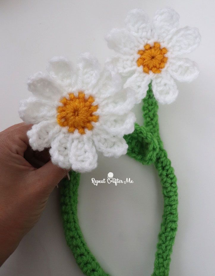 crocheted flower headband made with white and yellow flowers on top of green stems