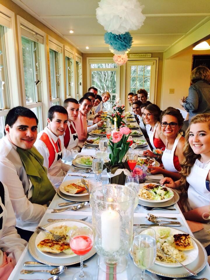 a group of people sitting at a long table with plates of food in front of them