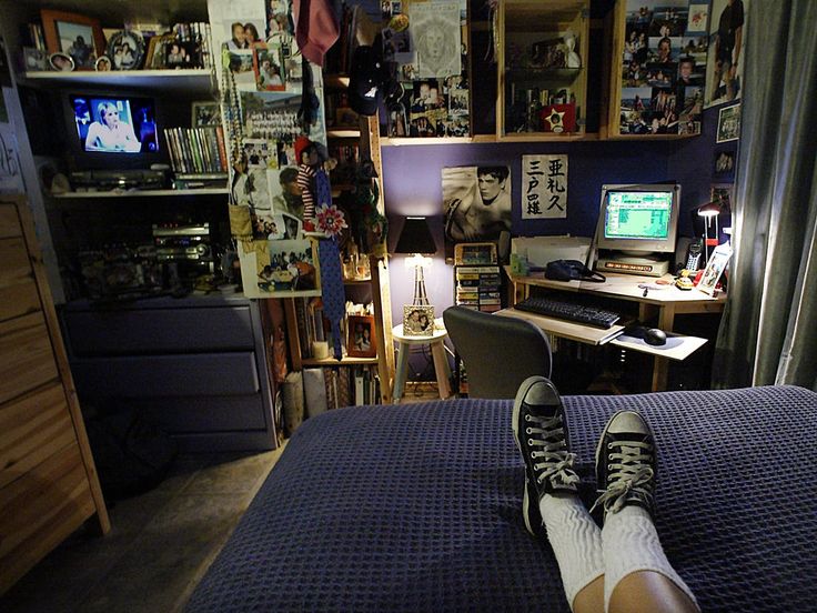 a person's feet resting on the edge of a bed in front of a computer