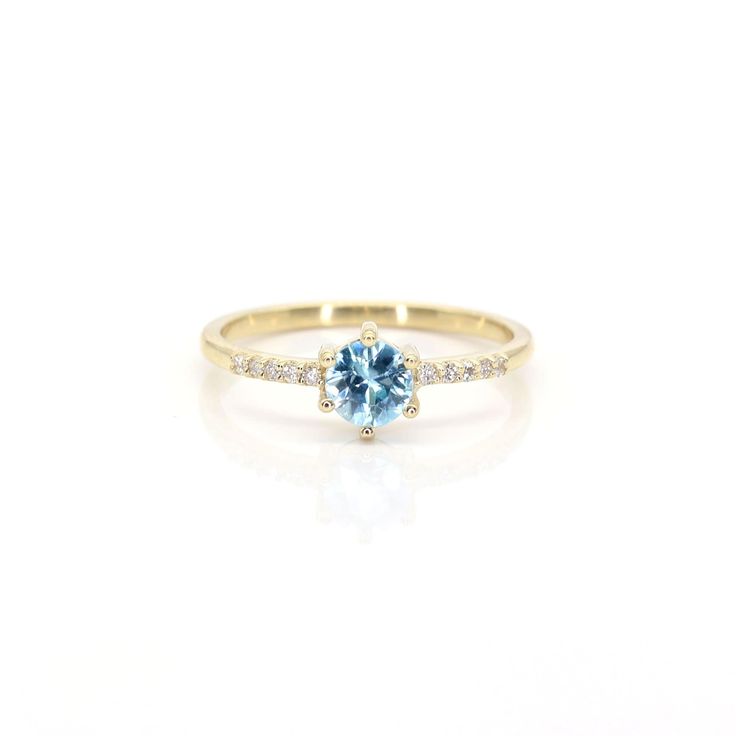 a yellow gold ring with an aqua blue stone and diamonds