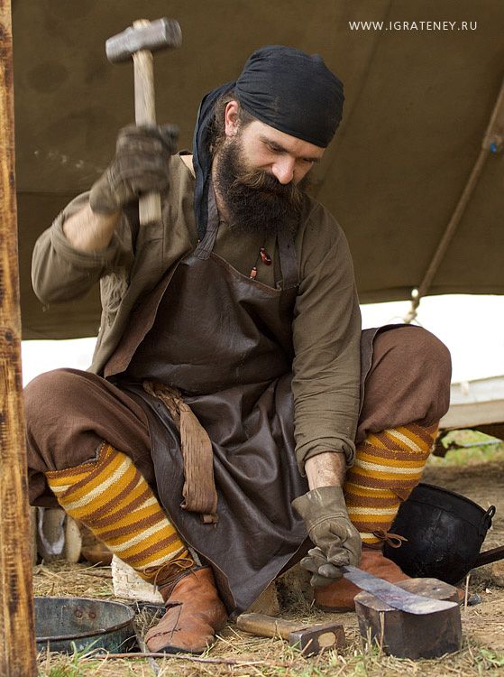 a man sitting on the ground with an ax in his hand next to some tools