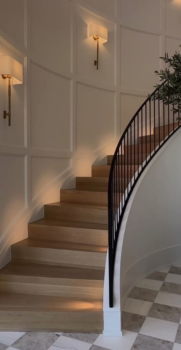 a white staircase with black handrails and lights on the wall next to it