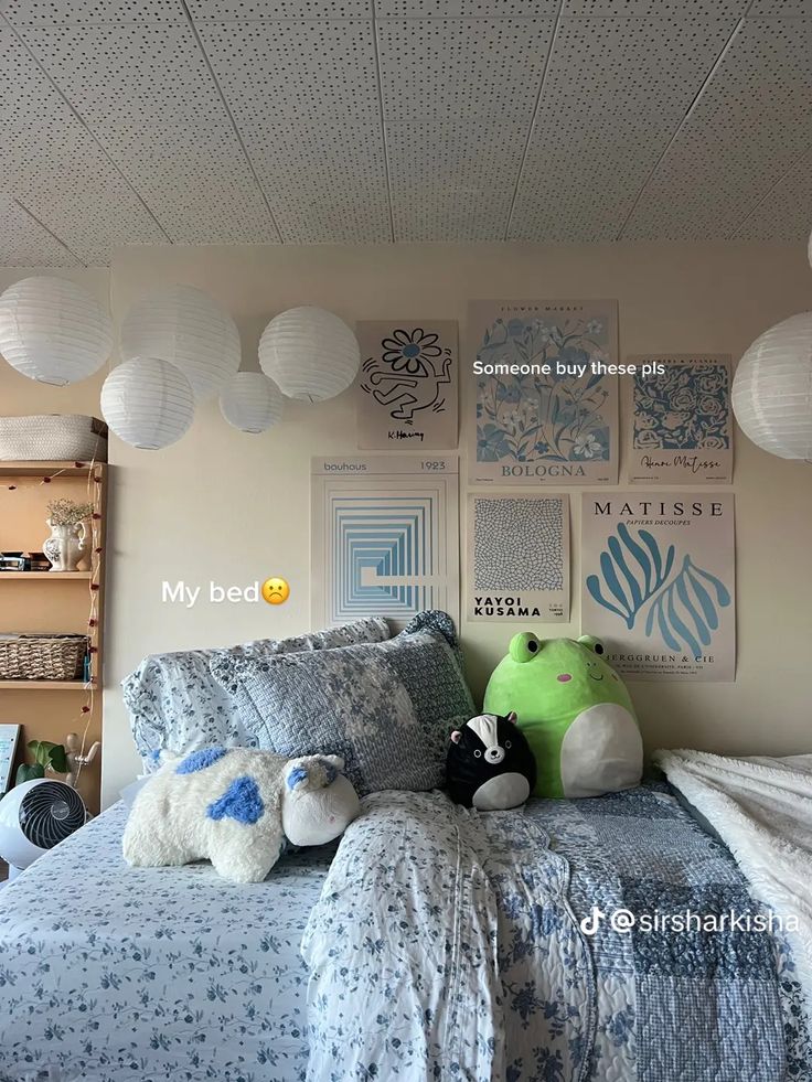 a bedroom with blue and white bedding, pillows and stuffed animals on the bed