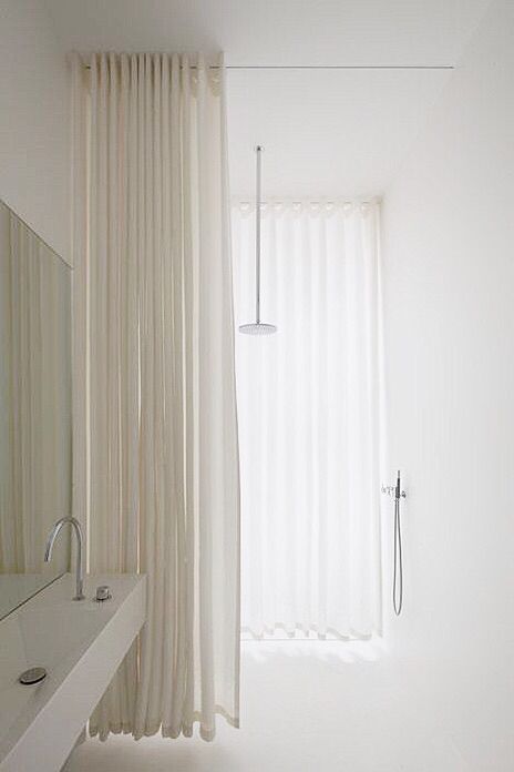 a bathroom with white walls and curtains on the window sill next to the sink