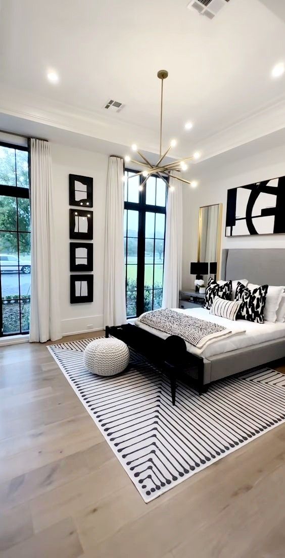 a modern bedroom with black and white decor on the walls, wood flooring and large windows