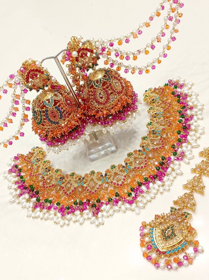 an assortment of jewelry is displayed on a white surface with beads and other items in the foreground