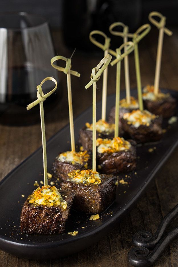 some food is sitting on a black plate with toothpicks in the shape of letters