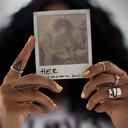 a woman holding up a polaroid with her fingernails and ring on it