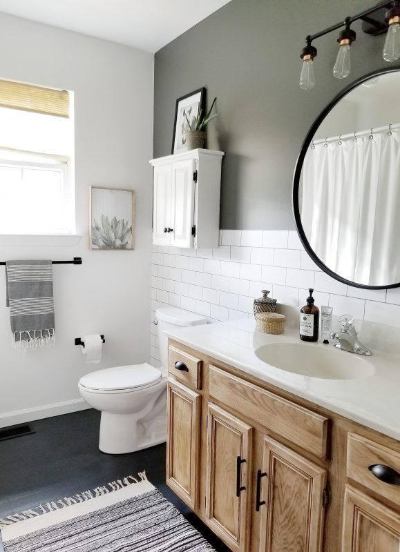 a white toilet sitting next to a bathroom sink under a round mirror in a bathroom