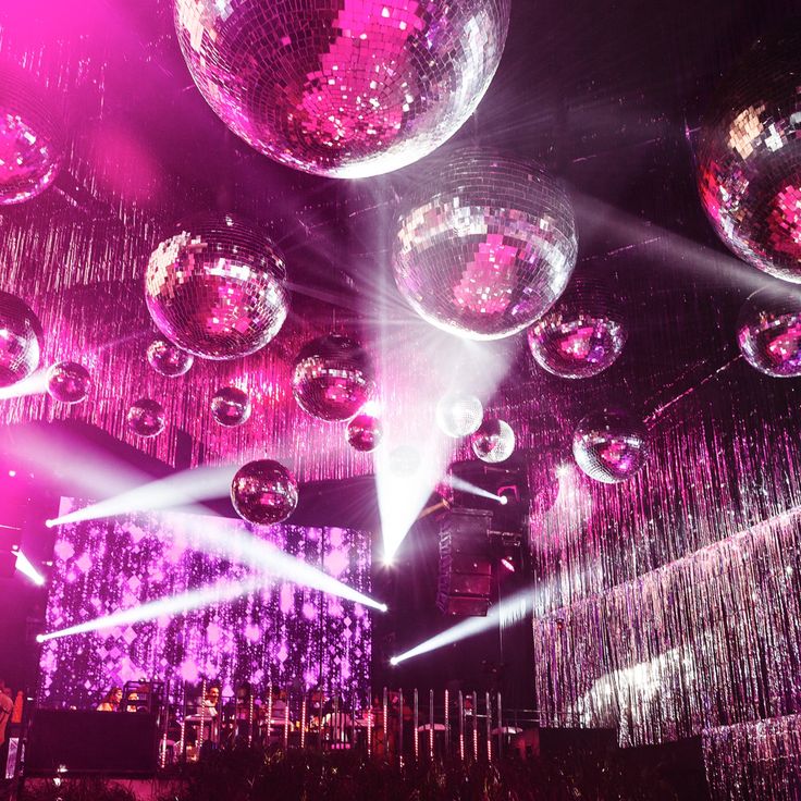 disco balls are suspended from the ceiling in front of purple lights and chandeliers