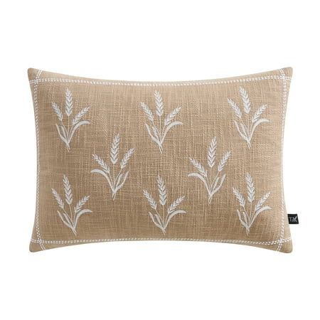 a beige pillow with white embroidered leaves on the front and back, sitting on a white background