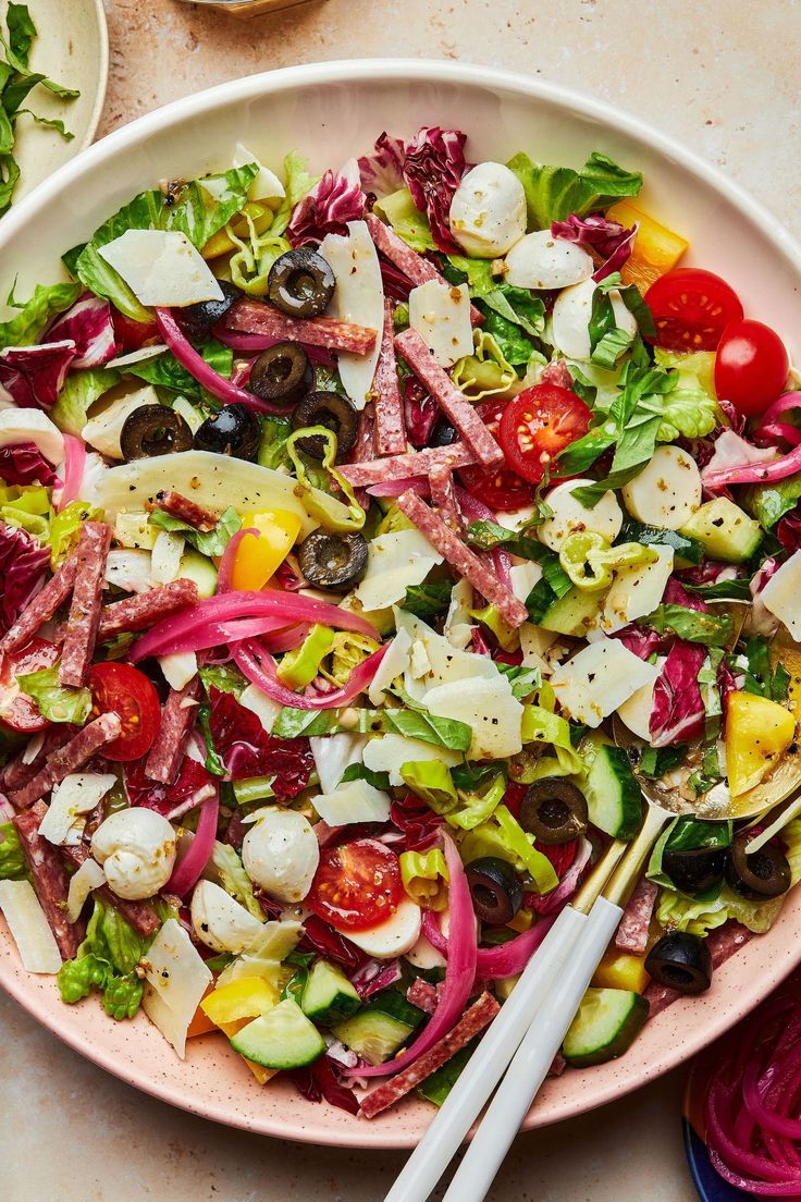 a large salad with red onions, lettuce and tomatoes in it on a white plate