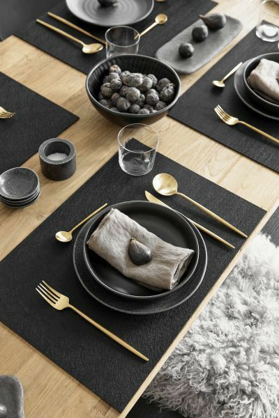 the table is set with black plates and gold cutlery, along with silverware