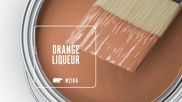 a paint can with a brush in it that says orange liqueur on the side