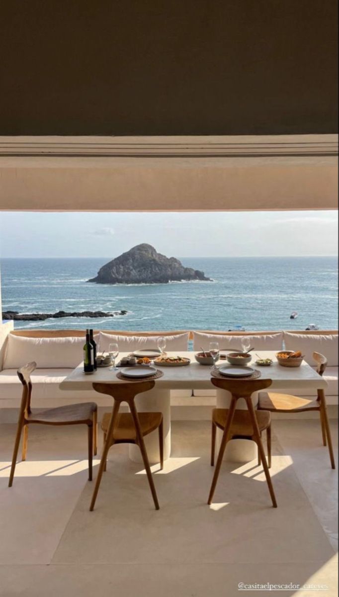 the dining table is set for two with an ocean view in the backround