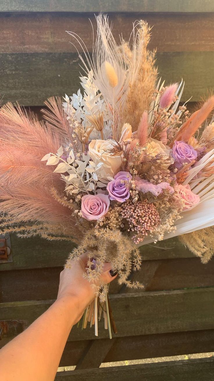 a person holding a bouquet with feathers and flowers